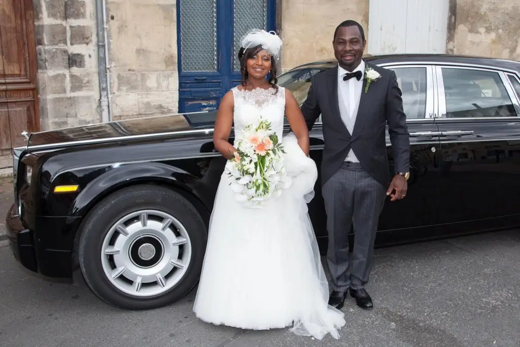 Couple smiling in front of a nice car