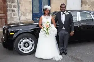 Couple smiling in front of a nice car