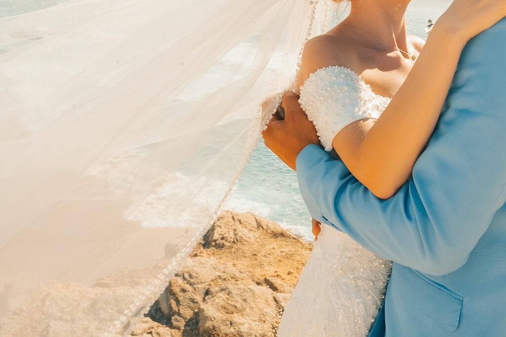 Bride and groom embrace at a coastal destination wedding overlooking the ocean
